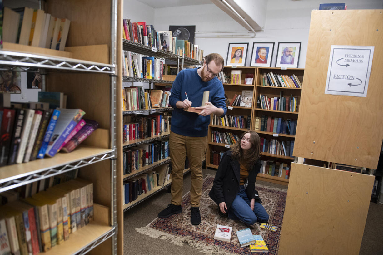 Lucas Gubala, left, and Sarah Summerhill, co-owners of the vintage bookstore Birdhouse Books, sort through books in their shop on Main Street in downtown Vancouver.