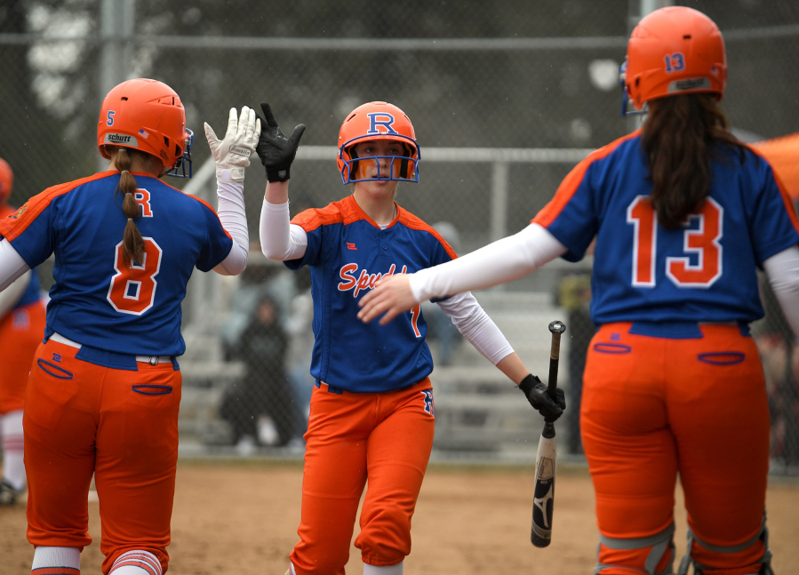 Ridgefield sophomore Mallory Vancleave, center, celebrates with teammates after scoring a run Friday, April 1, 2022, during the Spudders' 10-1 win against R.A. Long at Ridgefield High School.