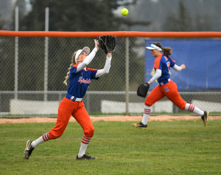 Ridgefield freshman Charlie Harris, left, catches the ball Friday, April 1, 2022, during the Spudders' 10-1 win against R.A. Long at Ridgefield High School.