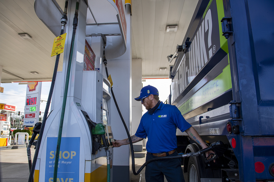 Safety manager Chase Henline of 1-800-Got-Junk? fills up a work vehicle as a nearby sign reflects high fuel prices during a stop at a Shell station in Hazel Dell on Friday morning.