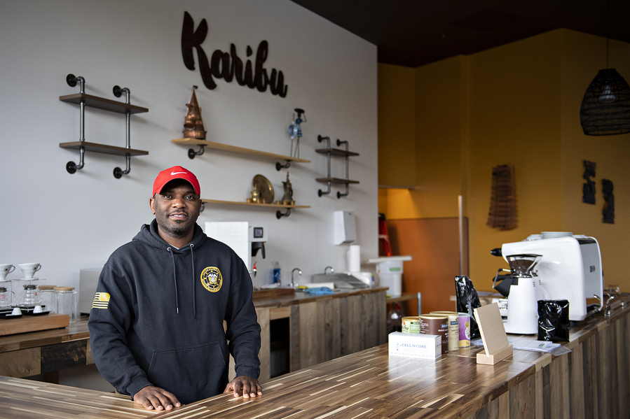 James Mbuya, owner of a new coffee shop in Uptown Village called Richland Hub, takes a break behind the front counter Friday morning. The "Karibu" sign behind him means "Welcome" in Swahili.