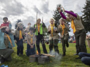 Members of Artemis Patrol Troop 351 from southeast Portland celebrate as the fire they built burns through all three strings in a fire-building challenge during Saturday's camporee at Fort Vancouver.