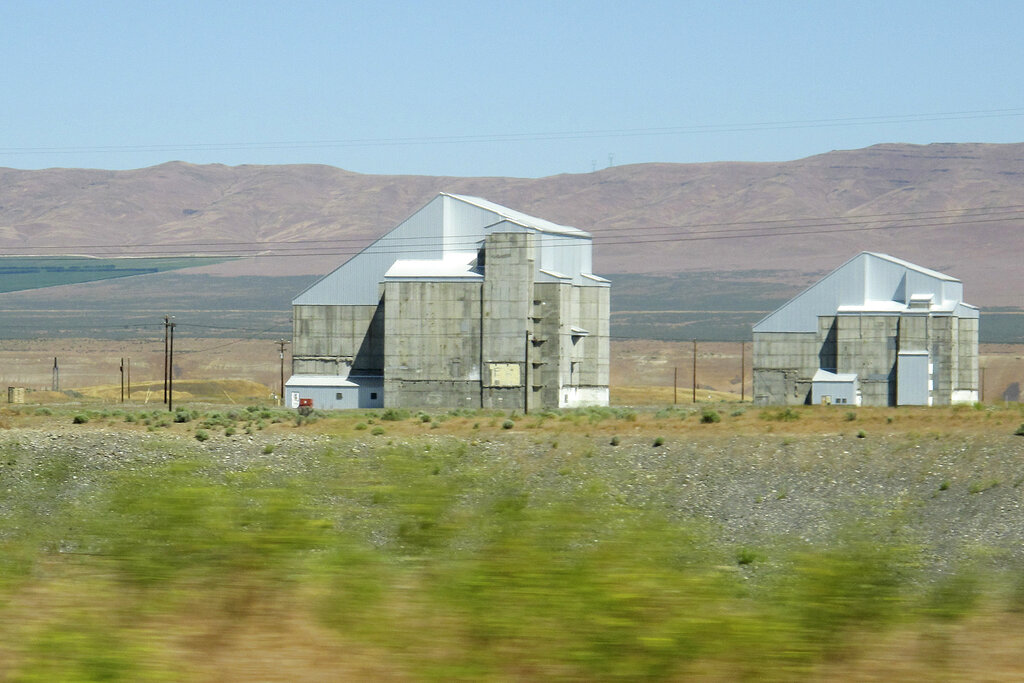FILE - The decommissioned plutonium-producing DR reactor, left, and D reactor, right, are shown on the Hanford Nuclear Reservation, June 13, 2017, near Richland, Wash. The federal government is moving forward with the cost-saving "cocooning" of eight plutonium production reactors at Hanford that will place them in a state of long-term storage for decades to allow radiation inside to dissipate until they can be dismantled and buried. (AP Photo/Nicholas K.