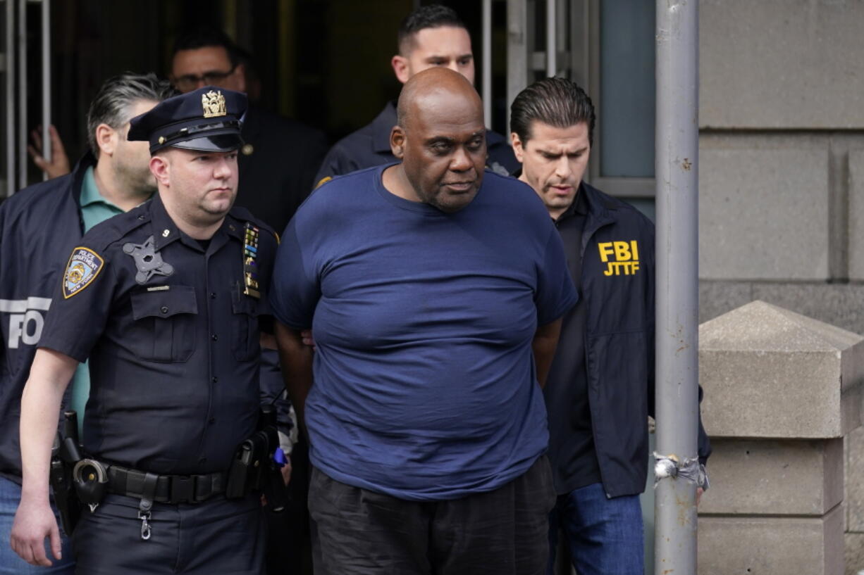 New York City Police and law enforcement officials lead subway shooting suspect Frank R. James, 62, center, away from a police station, in New York, Wednesday, April 13, 2022. The man accused of shooting multiple people on a Brooklyn subway train was arrested Wednesday and charged with a federal terrorism offense.