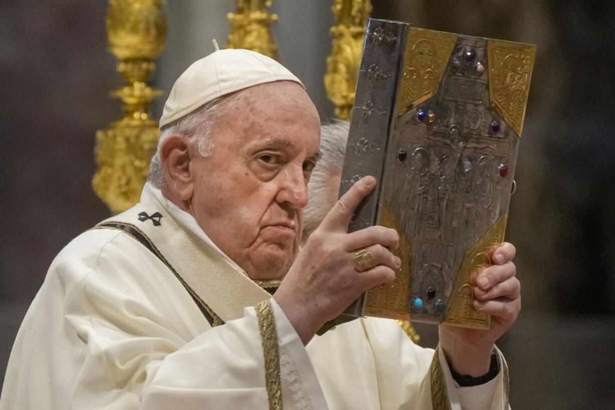 Pope Francis hoists the Gospel book during a Chrism Mass inside St. Peter's Basilica, at the Vatican, Thursday, April 14, 2022. During the mass the Pontiff blesses a token amount of oil that will be used to administer the sacraments for the year.