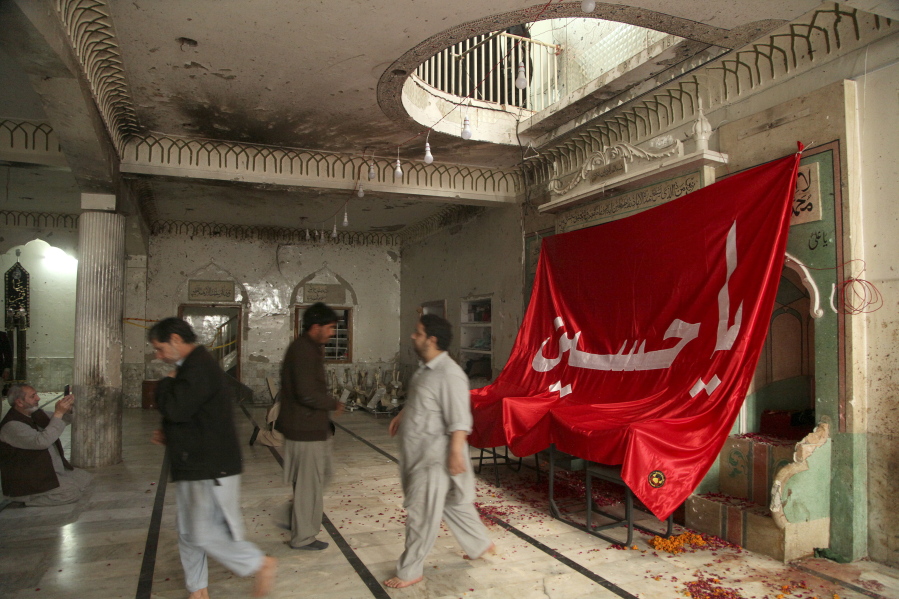 People visit Kusha Kisaldar Shiite Mosque, the site of March 4 suicide bombing, to offer prays for bombing victims, in Peshawar, Pakistan, Wednesday, March 9, 2022. In northwest Pakistan the remains of an IS suicide bomber are still visible on the once ornate walls of a mosque where last month more than 63 worshippers died as they knelt in prayer. The bomber, an Afghan identified by IS as Julaybib al-Kabuli, was from the capital Kabul.