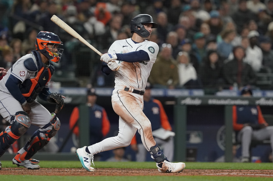 Seattle Mariners' Adam Frazier follows through on a single next to Houston Astros catcher Martin Maldonado during the sixth inning of a baseball game Friday, April 15, 2022, in Seattle. (AP Photo/Ted S.