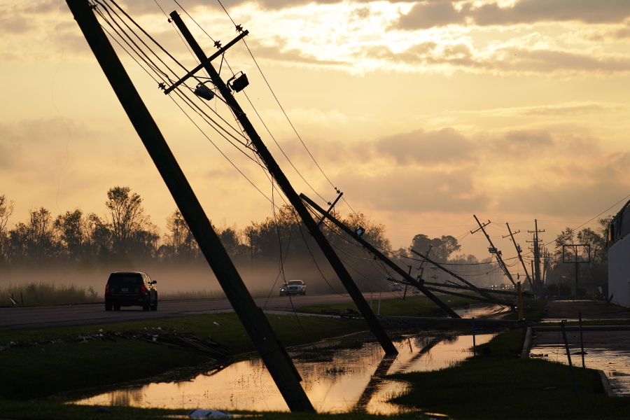 FILE - Downed power lines slump over a road in the aftermath of Hurricane Ida, Friday, Sept. 3, 2021, in Reserve, La. Weather disasters fueled by climate change now roll across the U.S. year-round, battering the nation's aging electric grid.