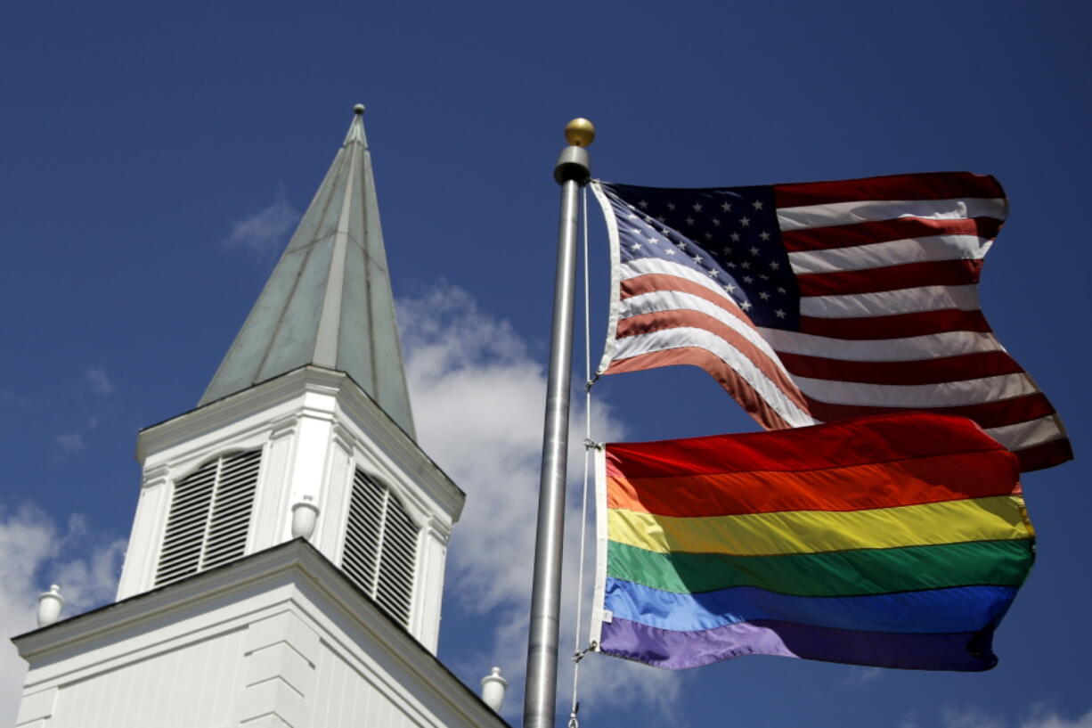FILE - A gay pride rainbow flag flies along with the U.S. flag in front of the Asbury United Methodist Church in Prairie Village, Kan., on April 19, 2019.  The United Methodist Church's Council of Bishops, ending a five-day meeting on Friday, April 29, 2022, acknowledged the inevitable breakup of their denomination, which will gain momentum during the weekend with the launch of a global movement led by theologically conservative Methodists.
