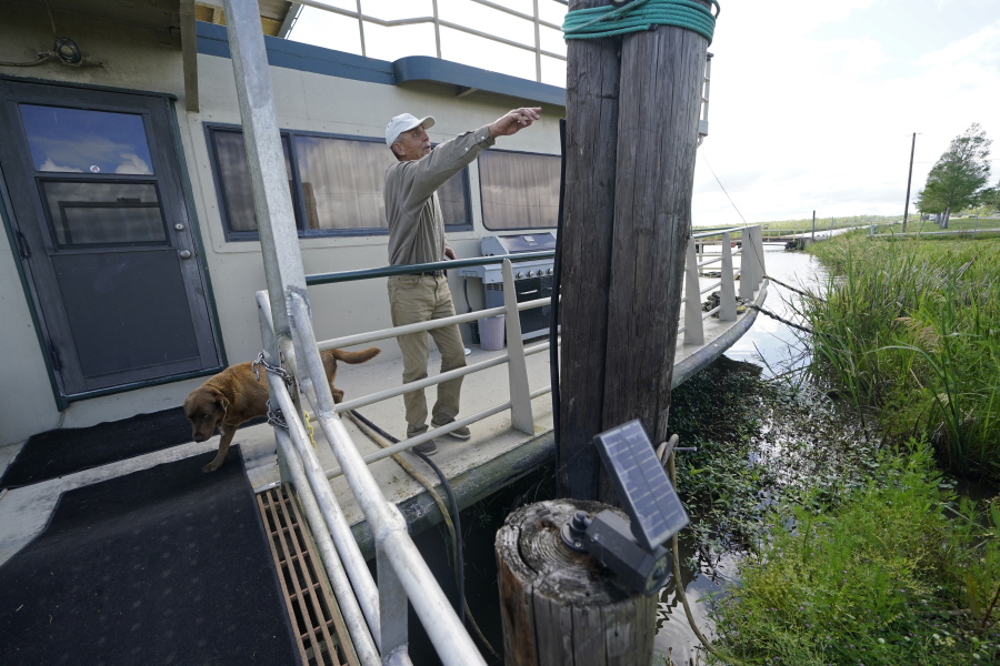 Ted Falgout points out the storm's waterline standing on the houseboat on his property that he rode out Hurricane Ida and has been living in while his home undergoes extensive repairs, in Larose, La., Thursday, April 14, 2022. As climate change increases the threat of hurricanes, cities on the Louisiana coast and Mississippi River are hoping President Biden's $1.2 trillion infrastructure package will provide badly needed funding to fortify locks, levees and other flood protections.