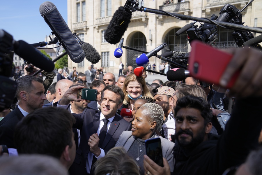 Centrist presidential candidate and French President Emmanuel Macron poses for selfie with a resident during a campaign stop Thursday, April 21, 2022 in Saint-Denis, outside Paris. French voters head to polls on Sunday in a runoff vote between centrist incumbent Emmanuel Macron and nationalist rival Marine Le Pen.