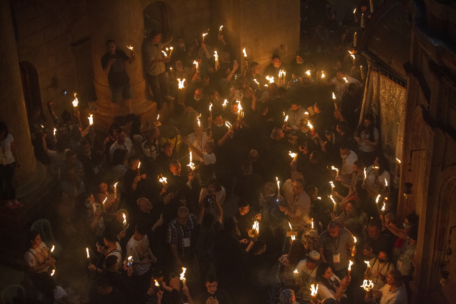 FILE - Christian pilgrims hold candles as they gather during the ceremony of the Holy Fire at Church of the Holy Sepulchre, where many Christians believe Jesus was crucified, buried and rose from the dead, in the Old City of Jerusalem on May 1, 2021. Christians have vowed to defy what they say are new and unfair Israeli restrictions on the "Holy Fire" ceremony to be held Saturday, April 23, 2022 at Christianity's holiest site, raising the possibility of even more religiously-charged unrest in Jerusalem.