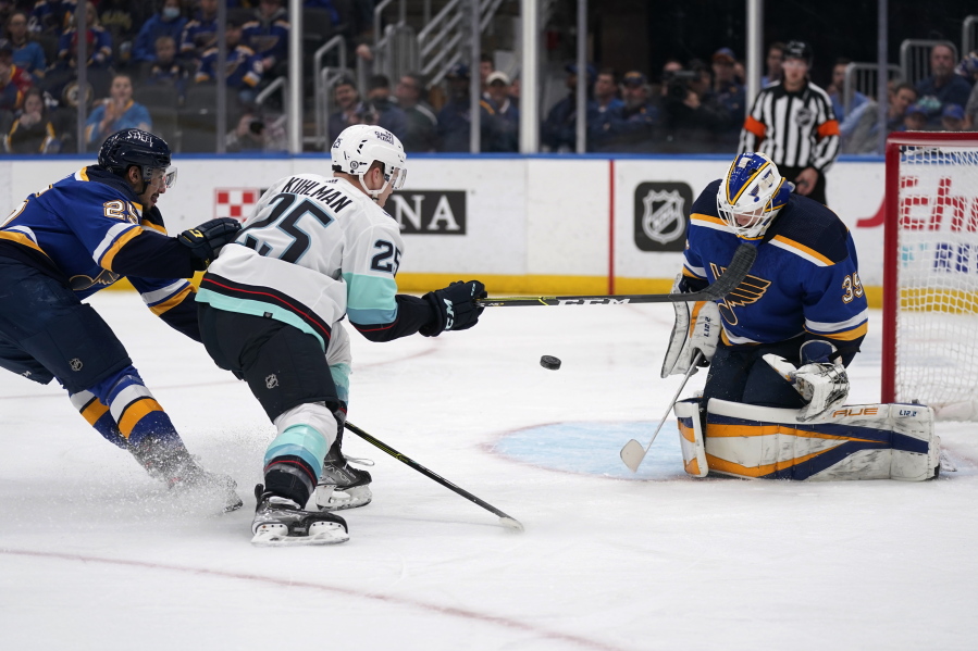 St. Louis Blues goaltender Ville Husso (35) stops a shot by Seattle Kraken's Karson Kuhlman as Blues' Jordan Kyrou, left, defends during the first period of an NHL hockey game Wednesday, April 6, 2022, in St. Louis.