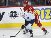 Seattle Kraken center Ryan Donato (9) vies for the puck against Calgary Flames left wing Matthew Tkachuk (19) during the first period of an NHL hockey game Tuesday, April 12, 2022, in Calgary, Alberta.