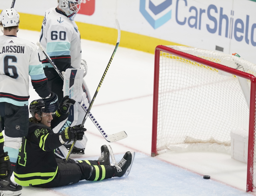 Dallas Stars center Roope Hintz (24) sits on the ice after he scored a goal against Seattle Kraken goaltender Chris Driedger (60) and defenseman Adam Larsson (6) during the second period of an NHL hockey game in Dallas, Saturday, April 23, 2022.