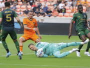 Portland Timbers goalkeeper Aljaz Ivacic, bottom, dives onto a shot on goal between, from left to right, defender Timbers' Claudio Bravo (5), Houston Dynamo forward Sebastian Ferreira (9) and Timbers defender Larrys Mabiala during the first half of an MLS soccer match Saturday, April 16, 2022, in Houston.