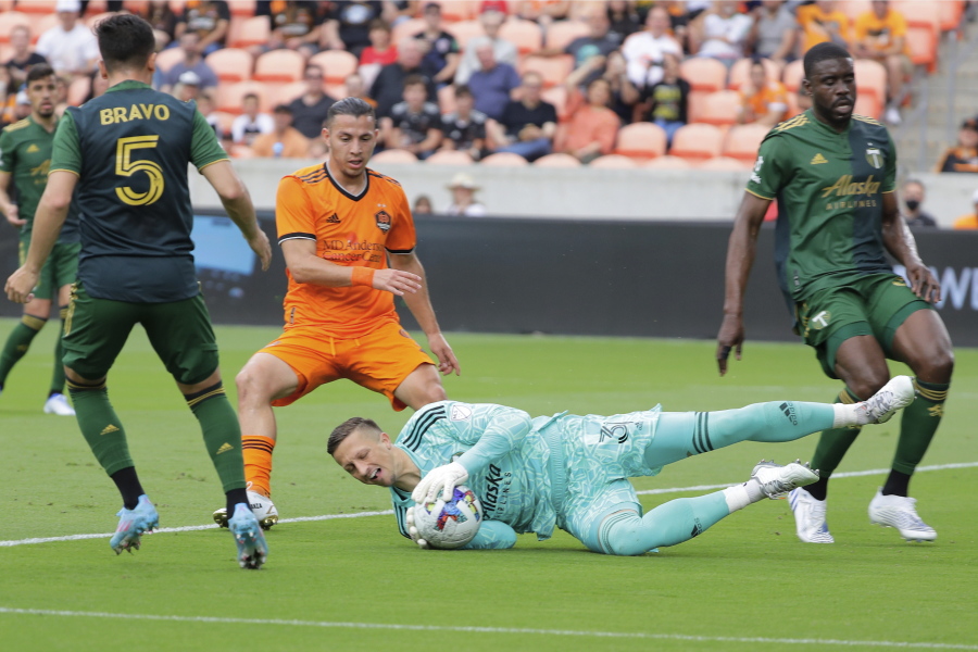 Portland Timbers goalkeeper Aljaz Ivacic, bottom, dives onto a shot on goal between, from left to right, defender Timbers' Claudio Bravo (5), Houston Dynamo forward Sebastian Ferreira (9) and Timbers defender Larrys Mabiala during the first half of an MLS soccer match Saturday, April 16, 2022, in Houston.