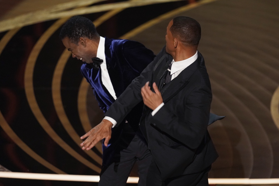 FILE - Will Smith, right, hits presenter Chris Rock on stage while presenting the award for best documentary feature at the Oscars on Sunday, March 27, 2022, at the Dolby Theatre in Los Angeles.  On Friday, April 1, The Associated Press reported on stories circulating online incorrectly claiming a photo shows Rock wearing a pad on his cheek during the incident at the Oscars where Smith slapped him.