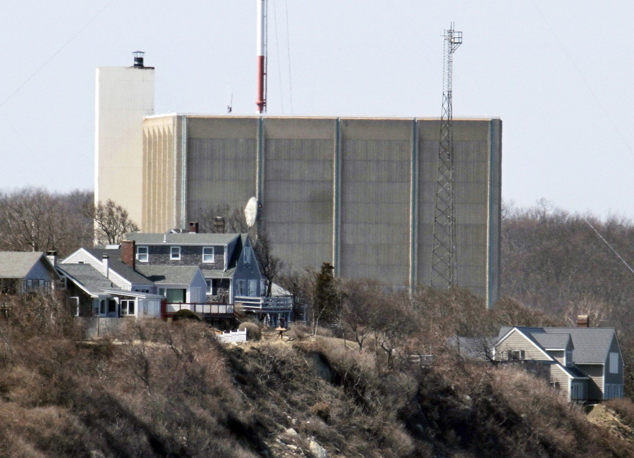 FILE - A portion of the Pilgrim Nuclear Power Station is visible beyond houses along the coast of Cape Cod Bay, in Plymouth, Mass., March 30, 2011. Pilgrim, which closed in 2019, was a boiling water reactor. Water constantly circulated through the reactor vessel and nuclear fuel, converting it to steam to spin the turbine. The water was cooled and recirculated, picking up radioactive contamination.