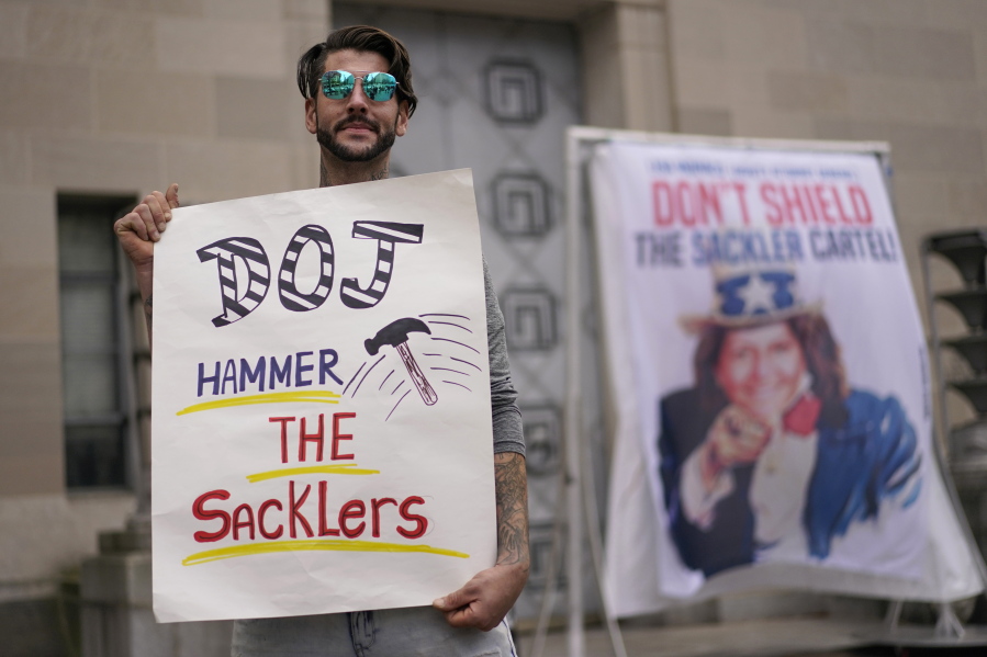 FILE - Nicholas Rivers of Maine, holds a sign that reads DOJ Hammer the Sacklers" during a protest with advocates for opioid victims outside the Department of Justice, Friday, Dec. 3, 2021, in Washington. A federal appeals panel is scheduled to hear arguments on whether members of the Sackler family can be granted protection from lawsuits as part of a bankruptcy settlement for the company they own, OxyContin maker Purdue Pharma. If the company doesn't get what it wants, it could have to fight off thousands of individual lawsuits.