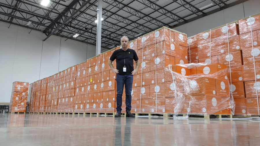 In this image provided by Direct Relief, Direct Relief CEO Thomas Tighe stands in front of boxes of N95 masks at Direct Relief's Santa Barbara, Calif., warehouse and headquarters in March 2020. Since the war between Russia and Ukraine began in February, Tighe and the nonprofit humanitarian medical organization Direct Relief, where he has been president and CEO since 2000, have provided more than 50 million doses of medication and 254 tons of medical aid to those in Ukraine and neighboring countries.