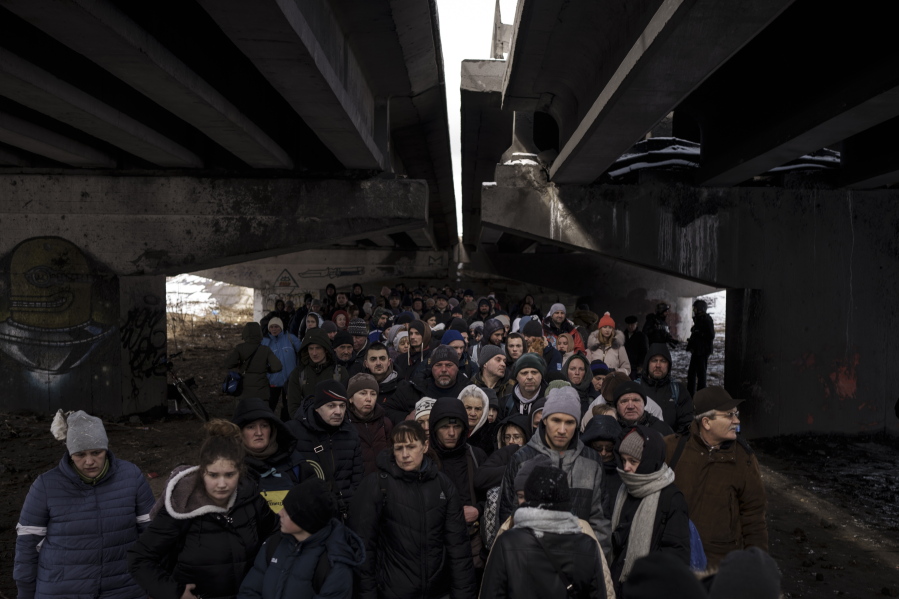 FILE - People crowd under a destroyed bridge as they try to flee, crossing the Irpin river on the outskirts of Kyiv, Ukraine, Tuesday, March 8, 2022. Russia's relentless digital assaults on Ukraine may have caused less damage than many anticipated. But most of its hacking is focused on a different goal that gets less attention but has chilling potential consequences: data collection.