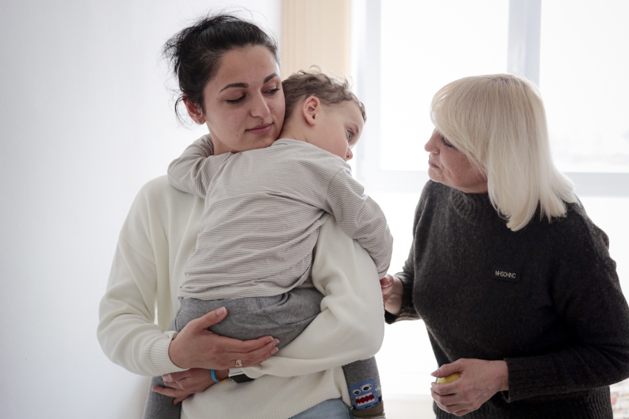Karina Buiukli, 27-years-old, holds her 2-year-old son, Maxim as her mother Galina Stepanova, right, watches after an interview with The Associated Press, in Brasov, Romania, Wednesday, March 30, 2022. Having escaped from Russian shelling, Ukrainian refugees are now focused on building new lives -- temporarily or permanently.