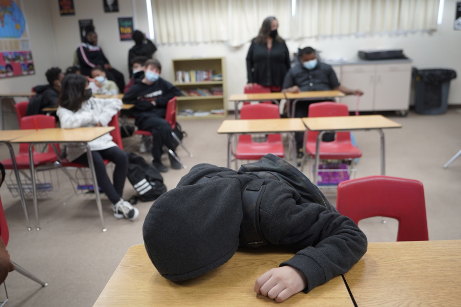 An unidentified student rests on his desk as the Mojave Unified School District Superintendent Katherine Aguirre, center rear, addresses students before their spring break at California City Middle School in California City, Calif., on Friday, March 11, 2022. Since the pandemic started, experts have warned of a mental health crisis facing American children that is now visibly playing out at schools across the country.