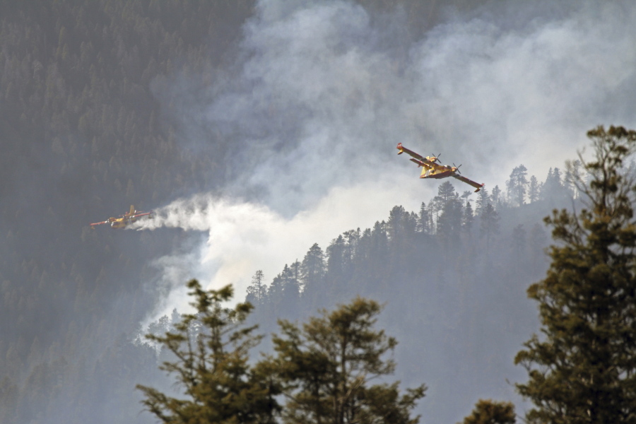 In this photo released by the U.S. Forest Service, aircraft known as "super scoopers" battle the Hermits Peak and Calf Canyon Fires in the Santa Fe National Forest in New Mexico on Tuesday, April 26, 2022. Firefighters have been making significant progress on the biggest wildfires burning unusually hot and fast for this time of year in the western U.S. But forecasters from the Southwest to the southern High Plains are warning of the return the next two days of the same gusty winds and critical fire conditions that sent wildland blazes racing across the landscape last week. (J. Michael Johnson/U.S.