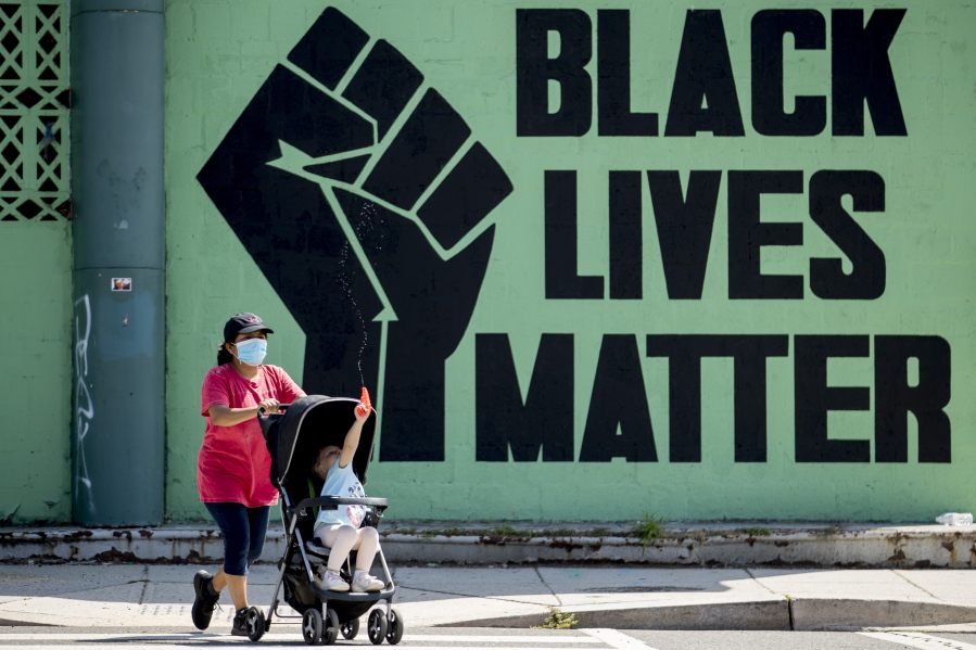 FILE - A girl in a stroller plays with a squirt gun as a woman pushes her past a Black Lives Matter mural in the Shaw neighborhood in Washington, Monday, July 13, 2020. The National Urban League released its annual report on the State of Black America on Tuesday, April 12, 2022, and its findings are grim. This year's Equality Index shows Black people still get only 73.9 percent of the American pie white people enjoy.