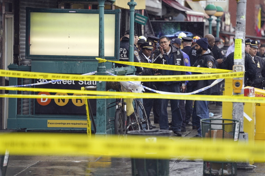 New York City Police Department personnel gather at the entrance to a subway stop in the Brooklyn borough of New York, Tuesday, April 12, 2022. Multiple people were shot and injured Tuesday at a subway station in New York City during a morning rush hour attack that left wounded commuters bleeding on a train platform.