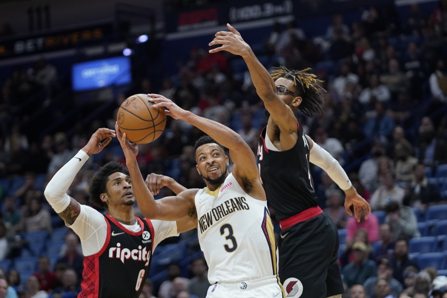 New Orleans Pelicans guard CJ McCollum (3) goes to the basket between Portland Trail Blazers guard Keon Johnson (6) and forward Greg Brown III in the second half of an NBA basketball game in New Orleans, Thursday, April 7, 2022.