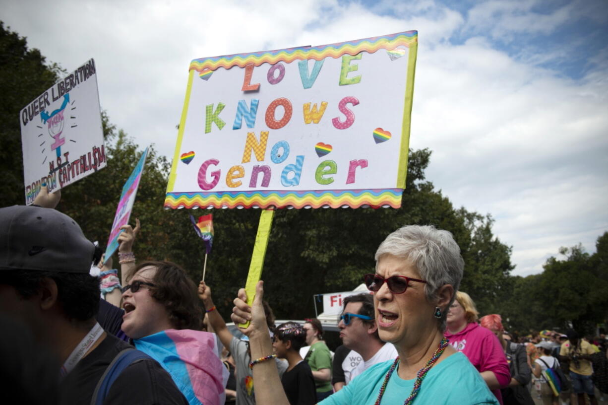 FILE - Barbara Dale, from Atlanta, mother of a transgender child, waves sign reading "Love Knows No Gender" at Gay Pride Transgender March at Piedmont Park in the city's Midtown District in Atlanta, Ga, Saturday, Oct. 12, 2019. Transgender medical treatment for children and teens is increasingly under attack in many states, labeled child abuse and subject to criminalizing bans. But it has been available in the United States for more than a decade and is endorsed by major medical associations.