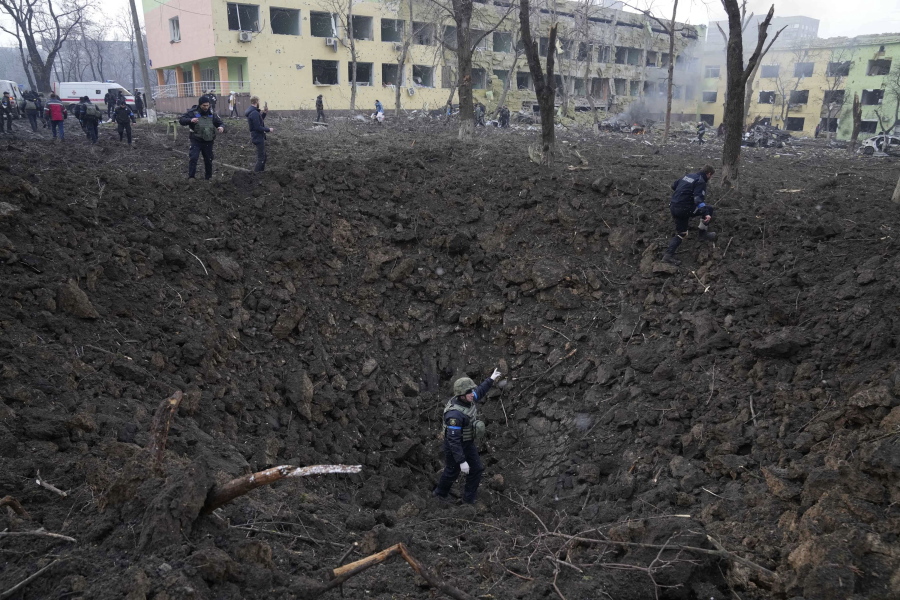 FILE - Ukrainian soldiers and emergency employees work outside a maternity hospital damaged by shelling in Mariupol, Ukraine, Wednesday, March 9, 2022. An Associated Press team of journalists was in Mariupol the day of the airstrike and raced to the scene. Their images prompted a massive Russian misinformation campaign that continues to this day.