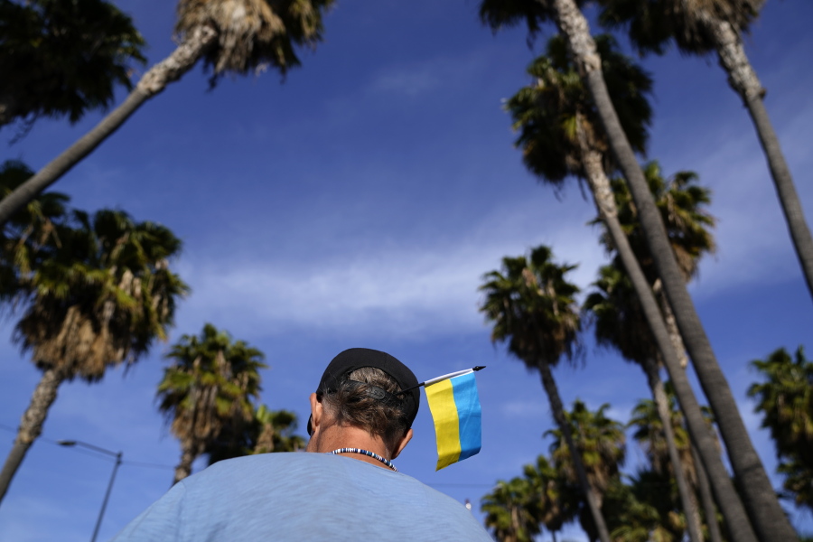Volunteer Zank Bennett, of the United States, wears a Ukrainian flag in his hat as he helps Ukrainians arriving Monday, April 4, 2022, in Tijuana, Mexico, as they look for a way to apply for asylum in the United States. A loose volunteer coalition, largely from Slavic churches in the western United States, is guiding hundreds of refugees daily from the airport in the Mexican border city of Tijuana to hotels, churches and shelters, where they wait two to four days for U.S officials to admit them on humanitarian parole.