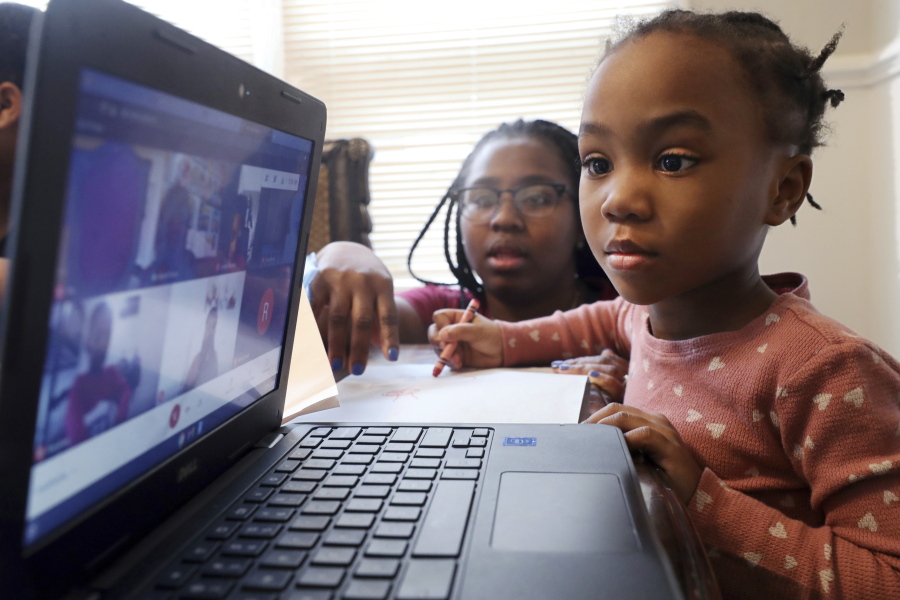 FILE -- Lear Preston, 4, who attends Scott Joplin Elementary School, participates in her virtual classes as her mother, Brittany Preston, background, assists at their residence in Chicago's South Side, Feb. 10, 2021. Schools across America are racing to make up for lost classroom time, budgeting billions of dollars for tutoring, summer camps and longer school days. But figuring out which students need help has become its own challenge after the pandemic left holes in some students' learning records.