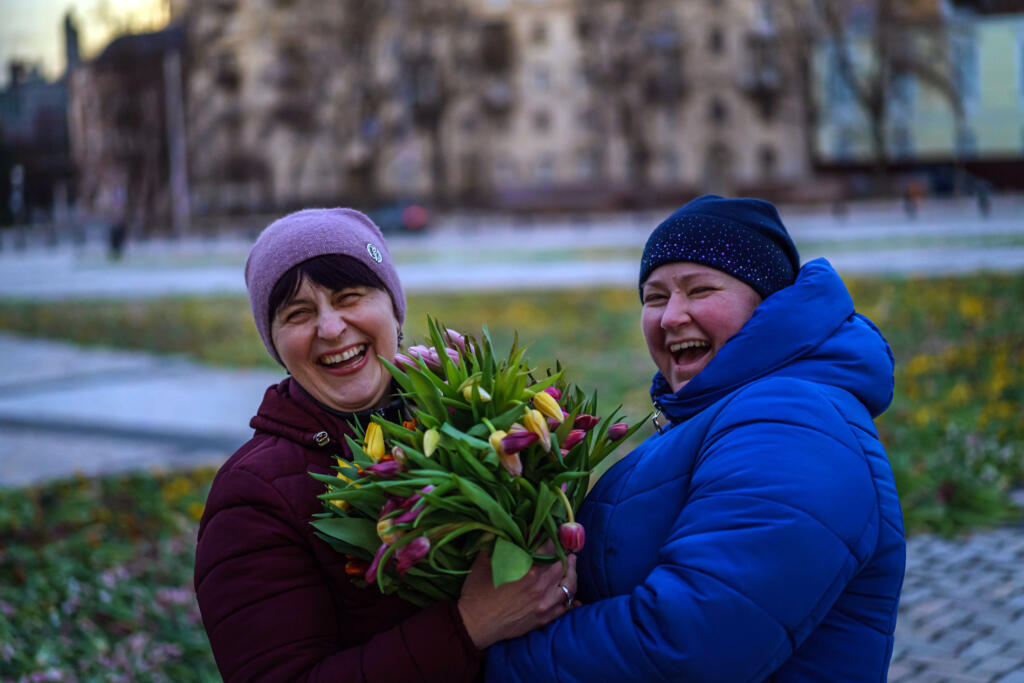 Viktoria Shkurat, left, and Iryna Asosak gather tulips for each other, at a central square after residents had spent the day arranging 1.5 million tulips in the shape of the country's coat of arms, in Kyiv, Ukraine, on March 19, 2022.