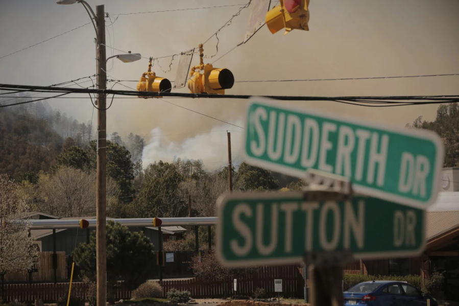 Smoke from the McBride Fire rises near an intersection in Ruidoso, New Mexico, on Wednesday, April 13, 2022.  Authorities say firefighters have kept a wind-driven blaze from pushing further into a mountain community in the southern part of the state.