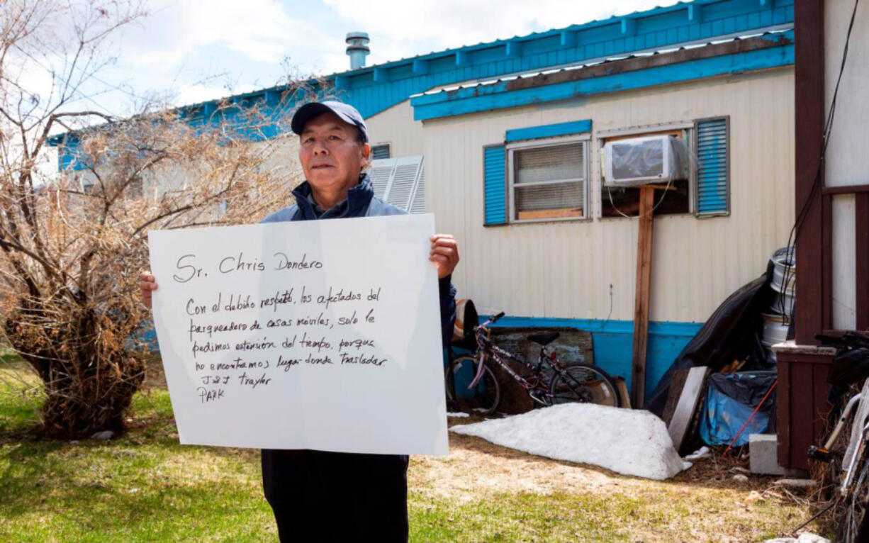 Enrique De la Cruz holds a sign in front of his mobile home asking a developer to give him and his neighbors at J&J Trailer Park in Blaine County more time to relocate.