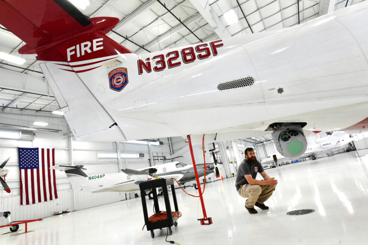 Mission Sensor Operator Wade Hutt checks out the large camera attached to the Pilatus multi-mission aircraft in a hangar at Centennial Airport at Centennial Airport on May 2, 2022, in Englewood, Colorado. This aircraft is used to detect fires, help with mapping of perimeters and give real time situational awareness of fires. The plane is also used for search and rescue operations, wildlife surveys, even avalanches. (Helen H.