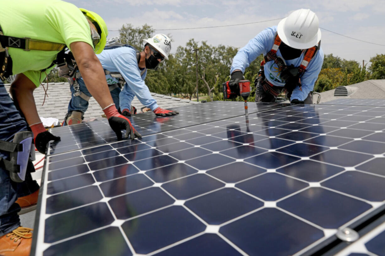 Juan Alcantara, left, intern/trainee, Sal Miranda, supervisor, and Lee Kwok, solar installer supervisor, of GRID Alternatives, a nonprofit, install solar panels that will generate 5 kilowatts of energy at a low-income home in Watts on Friday, June 18, 2021, in Los Angeles. A total of 15 327 watt panels were placed on the roof.