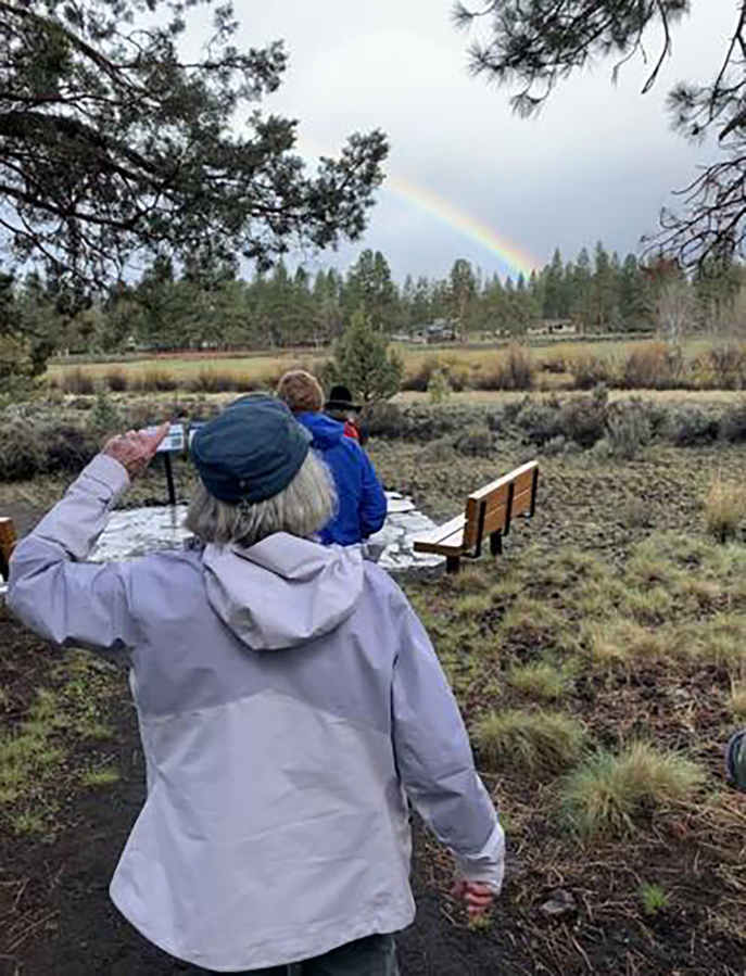 Tour leader Carrol Wall (front) points toward a rainbow on the other side of the meadow.