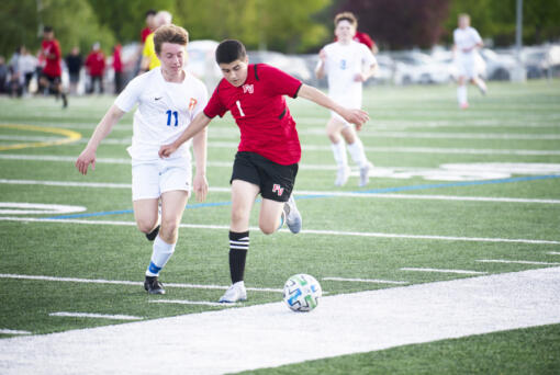 Fort Vancouver's Ernesto Coria Zavala (1) works against Ridgefield's Ashton Wagner during the Trappers' 2-0 win over Ridgefield in 2A boys soccer district playoff on Saturday, May 14, 2022. (Tim Martinez/The Columbian)