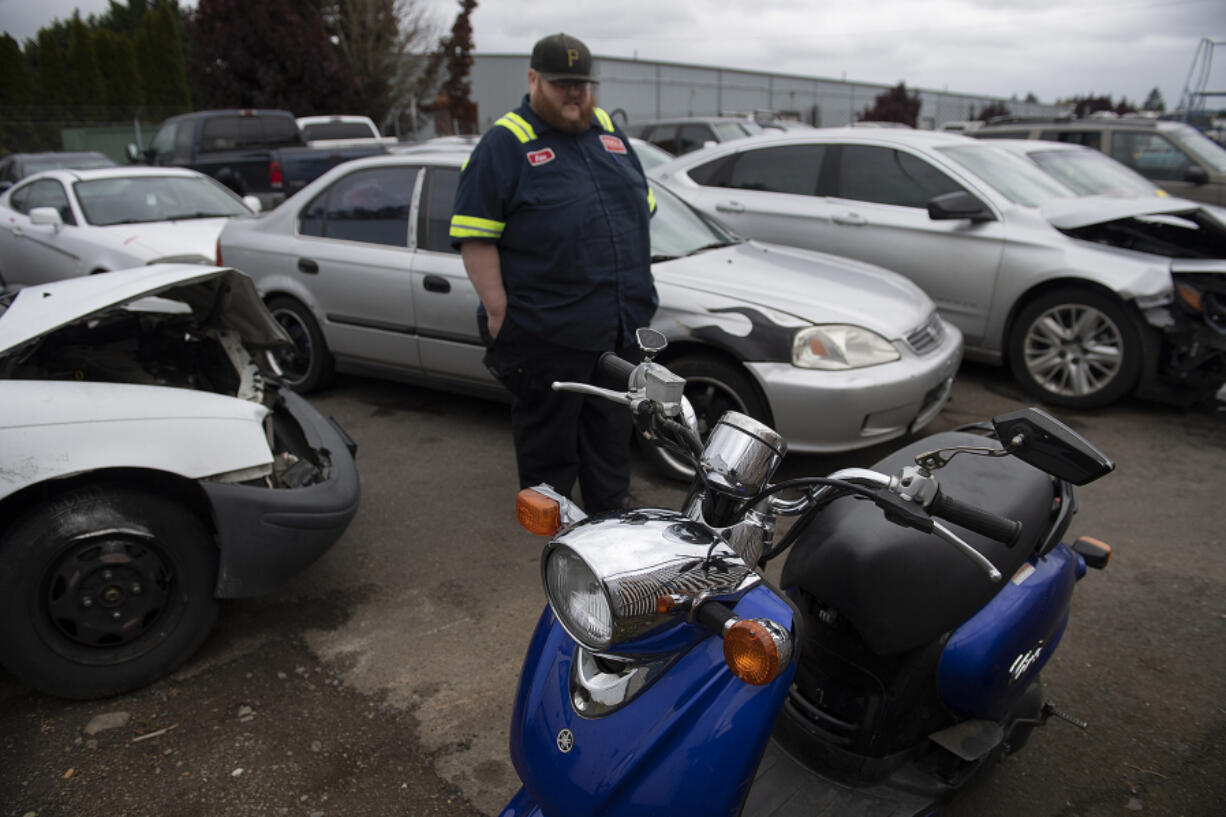 Jake Beals, lead driver for Triple J Towing, looks over a stolen moped Monday morning in the company's Vancouver lot. Law enforcement agencies are sounding the alarm about record-high levels of vehicle theft across the state.