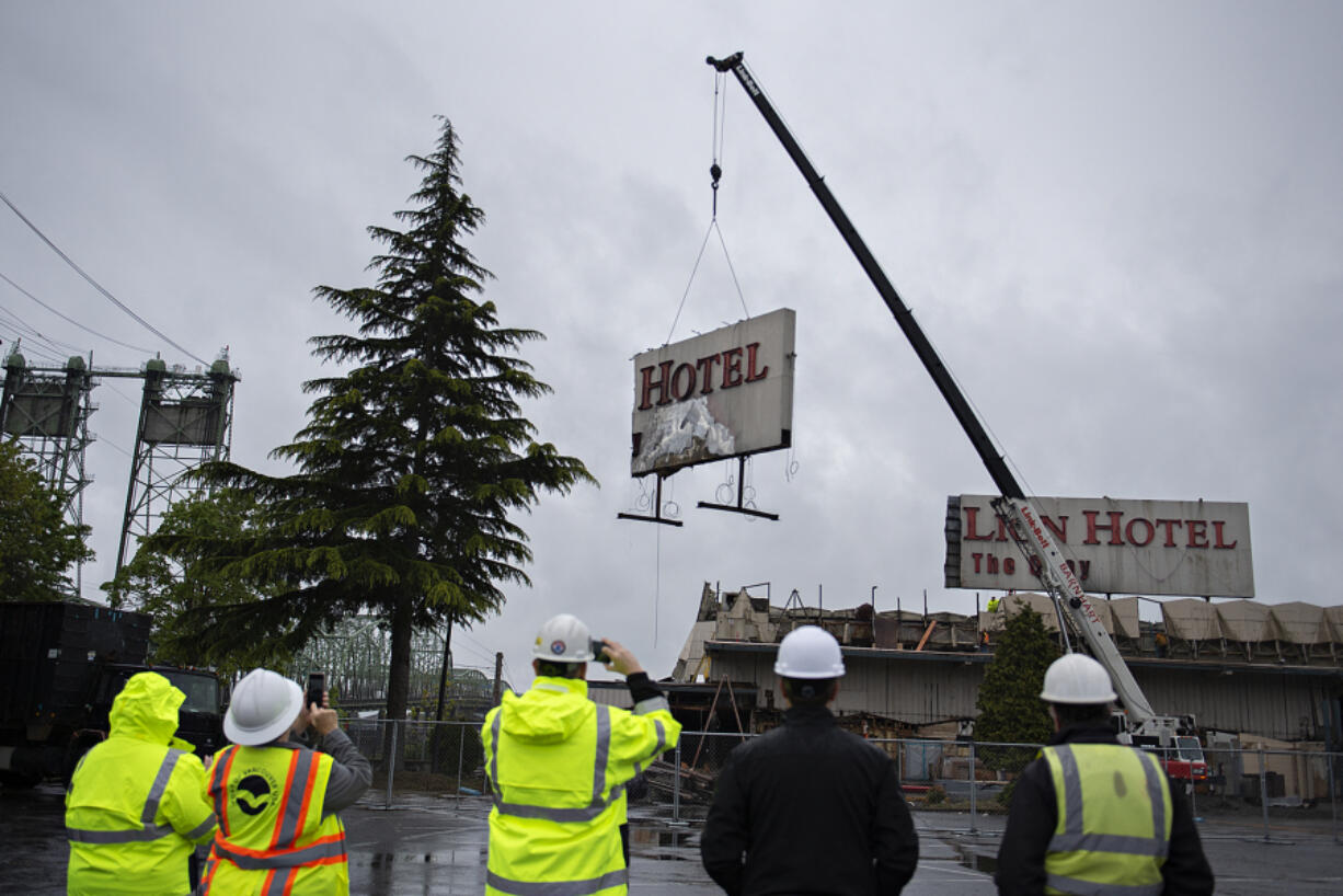Port of Vancouver officials look on as the iconic sign for the Red Lion Hotel Vancouver at the Quay comes down Thursday morning. The sign removal is a part of a larger project to demolish the former hotel and rebuild Terminal 1, extending the district established by the new Waterfront Vancouver.