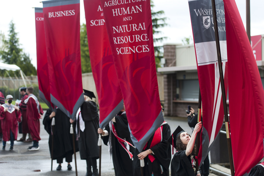 Graduate Zoe Minden, who earned a bachelor's degree in electrical engineering and won the Chancellor's Award for Student Achievement, steadies a banner before the Washington State University Vancouver commencement ceremony begins in 2022.