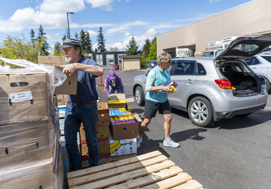 Volunteers Joe Pedron, left, Janis Yarbrough, center, and Sally Williams, all of Vancouver, prepare to load a car with donated food Tuesday during a drive-thru food distribution event at the Clark County Food Bank. Organizers of the National Association of Letter Carriers' food drive, slated for Saturday, hope to replenish the food bank's supply.