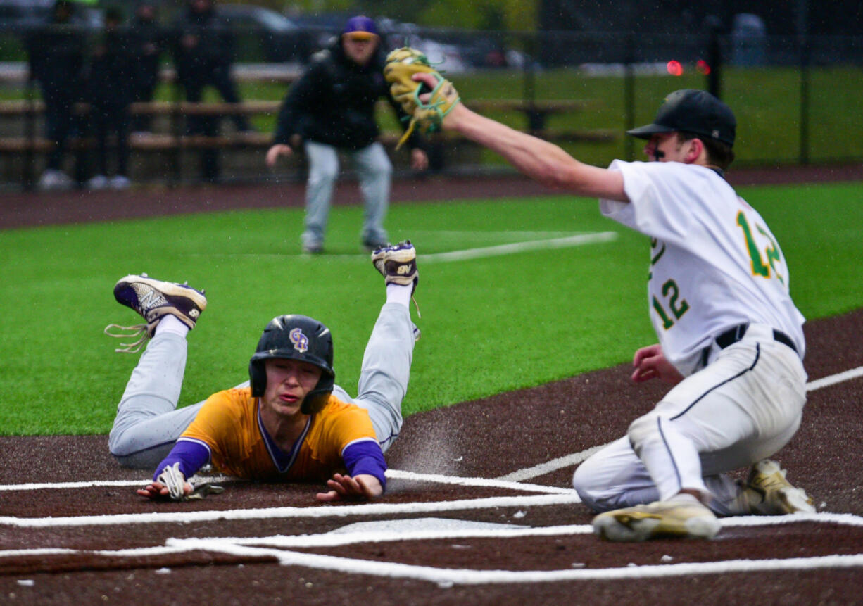 Columbia River senior Sam Boyle, left, slides into home and beats the tag from Tumwater pitcher Brayden Oram on Friday during River's 5-2 win against in the 2A District Championship at Ridgefield Outdoor Recreation Center.