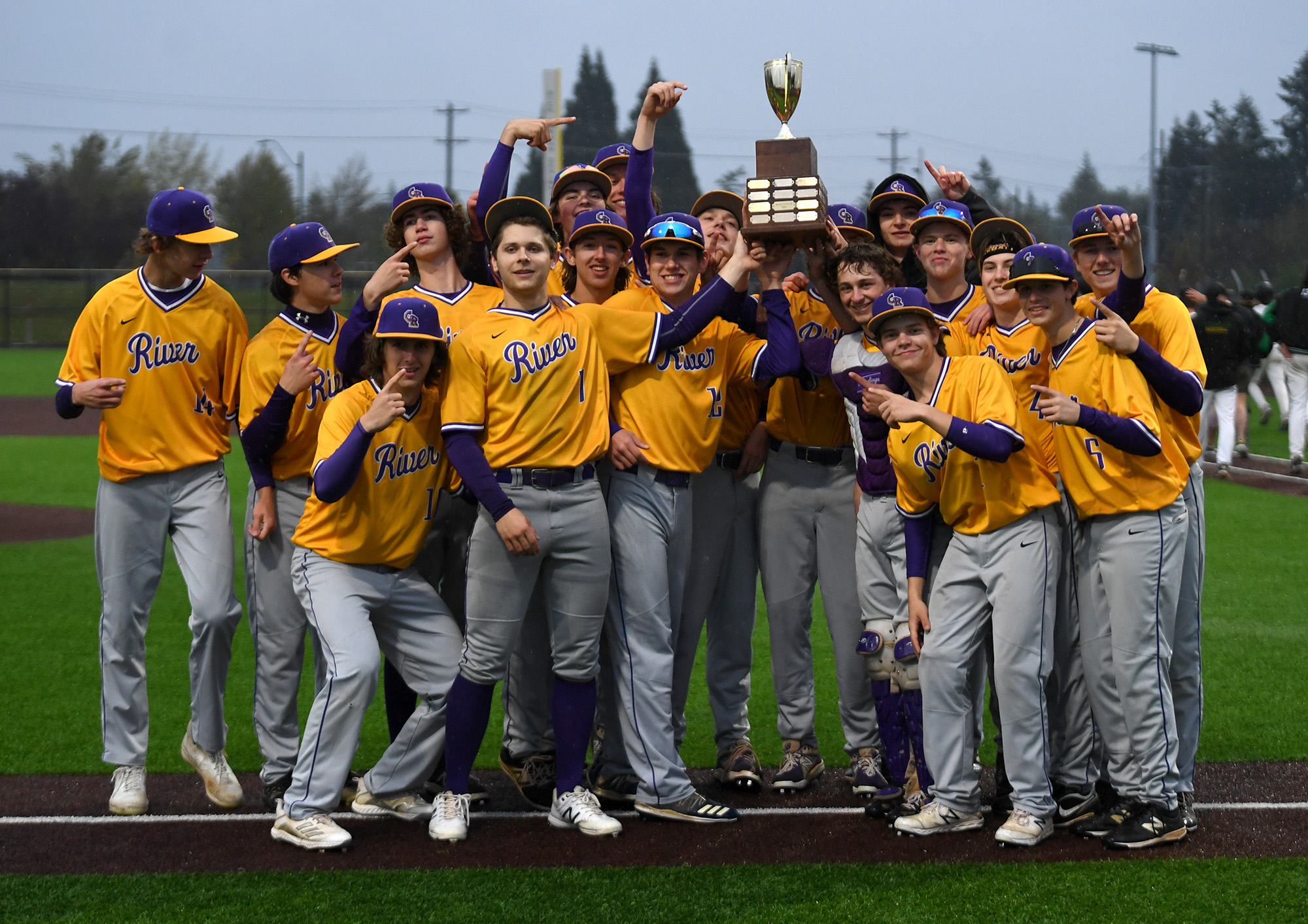 Members of the Columbia River baseball team pose with the 2A District trophy Friday, May 13, 2022, after River’s 5-2 win against Tumwater in the 2A District Championship at Ridgefield Outdoor Recreation Center.
