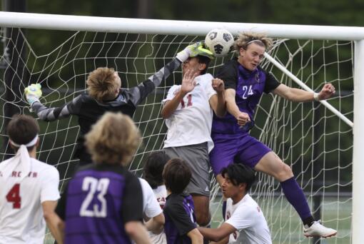 Columbia River's Alexander Brown, right, heads the ball at the goal as WF West's Hayden Sciera, left, and Ezra Bolin, center defend in the first round of the Class 2A state playoffs.